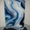 Groovy Glass #204:
Fused and slumped S-Curve in blue, turquoise, and white.  Measures 24Hx15L.  Displayed on custom black metal stand. $425